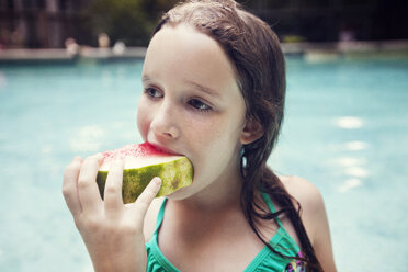 Girl eating watermelon slice against swimming pool - CAVF23306