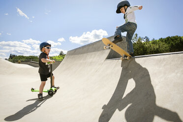 Boy looking at friend performing stunt on skateboard ramp - CAVF23414