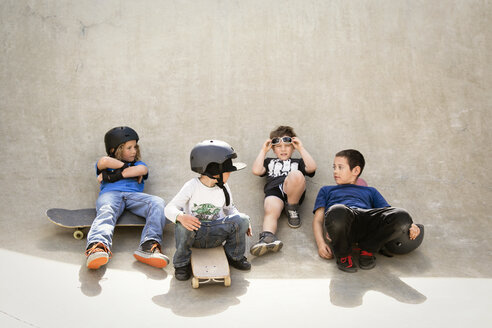 Jungen sprechen auf einer Skateboard-Rampe sitzend - CAVF23421