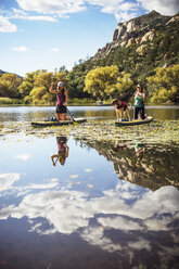 Freundinnen mit Hund paddeln auf einem See in den Bergen - CAVF23439