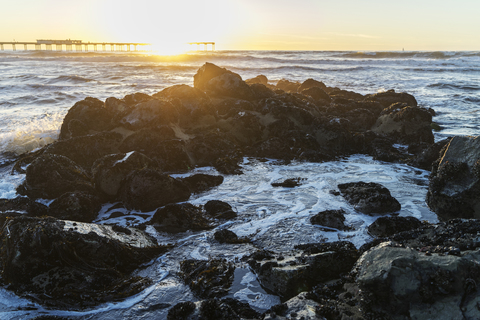 Scenic view of rocky beach against sky during sunset stock photo