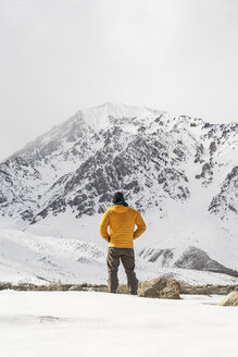 Rückansicht eines Mannes, der auf einem schneebedeckten Feld vor dem Himmel steht - CAVF23466