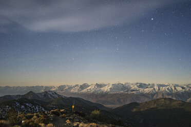 Fernansicht eines Wanderers inmitten von Bergen vor einem Sternenhimmel - CAVF23476