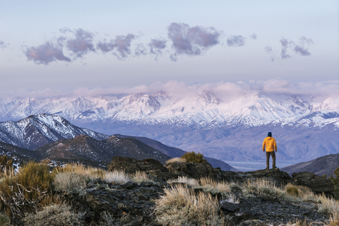 Rückansicht eines Wanderers, der auf einem Berg vor dem Himmel steht, lizenzfreies Stockfoto