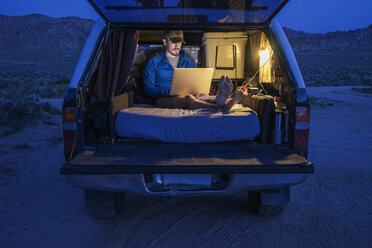Wanderer benutzt Laptop im Kofferraum im Urlaub - CAVF23480