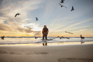 Rückansicht eines am Strand stehenden Mädchens gegen den Himmel bei Sonnenuntergang - CAVF23517
