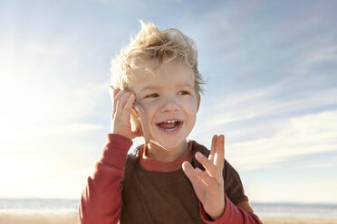 Happy girl talking on mobile phone at beach against sky - CAVF23518