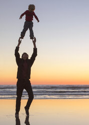 Teenager, der mit seiner Schwester am Meer spielt, gegen den klaren Himmel bei Sonnenuntergang - CAVF23519