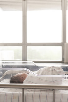Neugeborenes Mädchen schläft im Krankenhausbett vor dem Fenster - CAVF23525