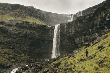 Wanderer steht auf einem Berg vor einem Wasserfall - CAVF23549