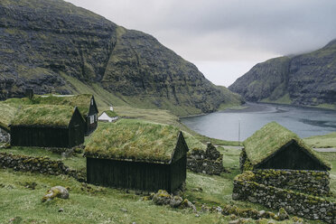 Traditional turf roofed farmhouses and church against mountains - CAVF23572