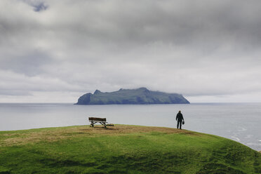 Wanderer mit Blick auf die Aussicht, während er auf einem Hügel am Meer gegen stürmische Wolken steht - CAVF23600