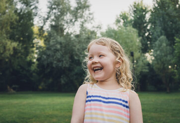 Cheerful girl looking away while standing at park - CAVF23636