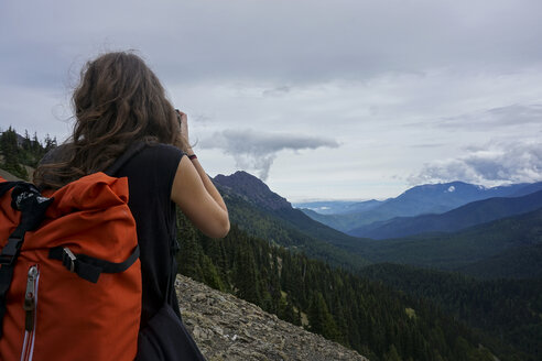 Rückansicht einer Wanderin auf dem Gipfel eines Berges bei bewölktem Himmel - CAVF23642