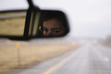 Reflection of woman on rear-view mirror in car - CAVF23654