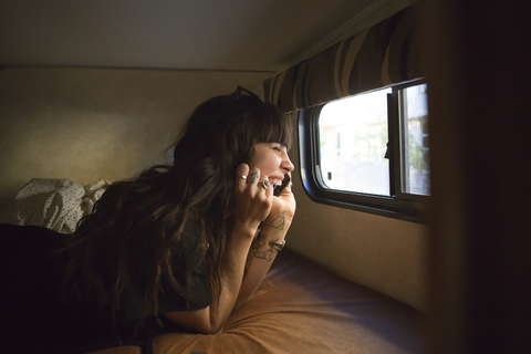 Happy woman talking on smart phone while travelling in camper van stock photo