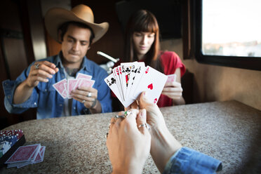 Nahaufnahme einer Frau, die Karten hält, während sie mit Freunden im Wohnmobil spielt - CAVF23686