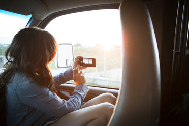 Frau fotografiert am Fenster während der Fahrt im Wohnmobil - CAVF23693