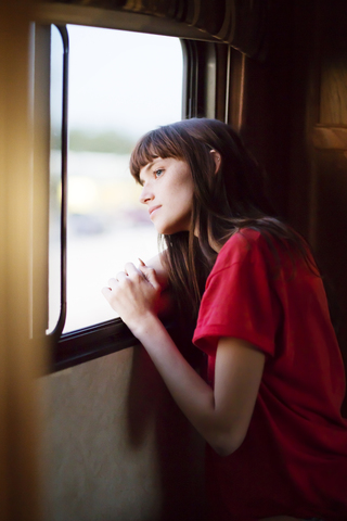 Nachdenkliche Frau schaut aus dem Fenster, während sie im Wohnmobil unterwegs ist, lizenzfreies Stockfoto