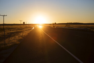 Road amidst field against clear sky during sunset - CAVF23709