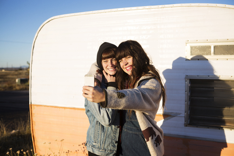 Weibliche Freunde machen ein Selfie, während sie am Wohnmobil stehen, lizenzfreies Stockfoto