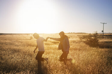 Couple walking while holding hands on field against clear sky - CAVF23717