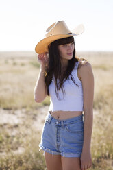 Woman wearing cowboy hat looking away while standing on field - CAVF23745