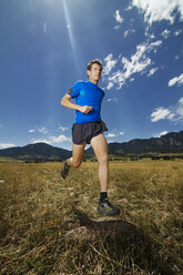 Low angel view of man running on grass field against sky - CAVF23882