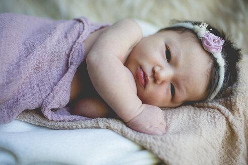 Nahaufnahme Porträt neugeborenes Baby Mädchen auf dem Bett liegend - CAVF23903