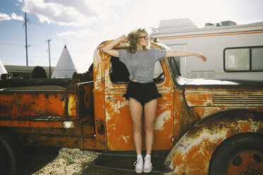 Frontansicht eines Teenagers in der Luft gegen einen alten, verlassenen Pick-up-Truck - CAVF23915