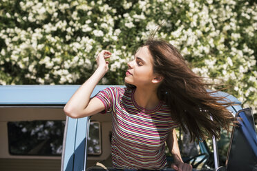 Teenager mit zerzaustem Haar, der in einem Wohnwagen aus dem Fenster schaut - CAVF23947