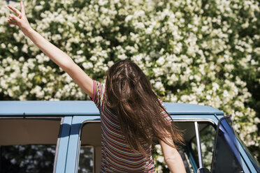 Teenager with tousled hair gesturing peace sign while riding in travel trailer - CAVF23948