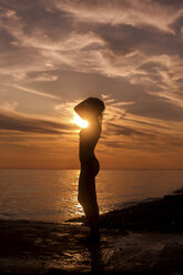 Seitenansicht der Silhouette sinnliche Frau stehen am Strand bei Sonnenuntergang - CAVF24032
