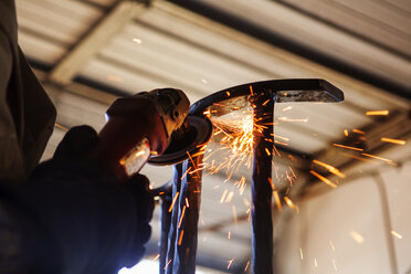 Beschnittenes Bild eines Handwerkers, der in einer Fabrik Metall poliert - CAVF24125