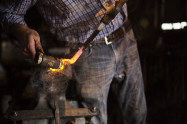 Mittelteil eines Handwerkers, der in einer Fabrik Metall hämmert - CAVF24128