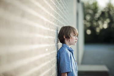 Thoughtful boy looking away while leaning against wall - CAVF24159