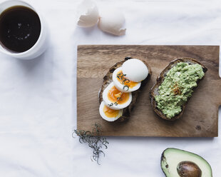 Draufsicht auf gekochte Eier und Avocadopaste auf Broten mit Kaffee - CAVF24223