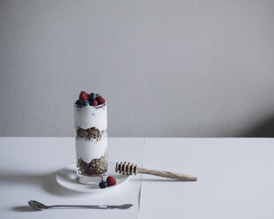 Haferflocken und Joghurt mit Früchten im Glas auf einem Tisch an der Wand - CAVF24226