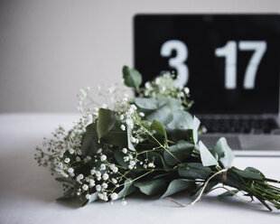 Nahaufnahme eines Blumenstraußes mit Laptop im Hintergrund auf einem Tisch - CAVF24233