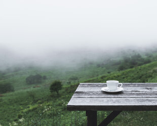 Kaffeetasse auf einem Tisch auf einem Berg bei nebligem Wetter - CAVF24265