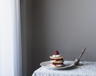 Pfannkuchen in einem Teller mit Honig auf einem Tisch an der Wand serviert - CAVF24266