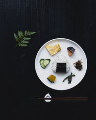 Overhead view of garnished plate with chopsticks on black table - CAVF24274