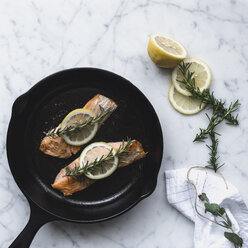 Draufsicht auf den Lachs in der Pfanne mit Zitrone und Rosmarin auf dem Tisch - CAVF24275