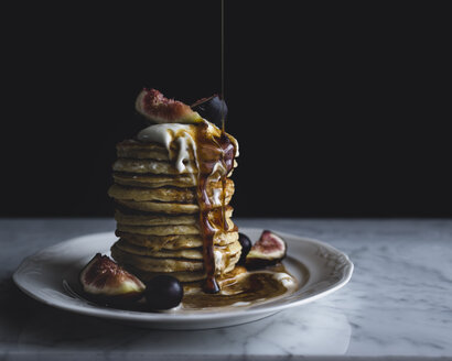 Close-up of syrup pouring on pancakes in plate on table - CAVF24303