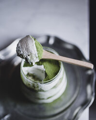 Spoon of matcha tea ice cream over glass in plate - CAVF24317