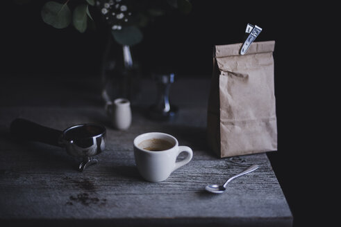 Espressotasse mit Papiertüte und Siebträgermaschine auf Holztisch - CAVF24328