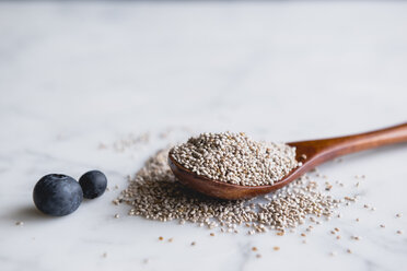 Wooden spoon with chia seeds and blueberries on marble counter - CAVF24331