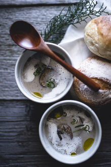 Overheadaufnahme von Pilzsuppe mit Löffel und Brötchen auf Holztisch - CAVF24338