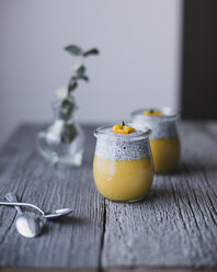 Jars of chia with mango pudding on wooden table - CAVF24347
