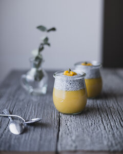 Chia-Gläser mit Mango-Pudding auf Holztisch - CAVF24347